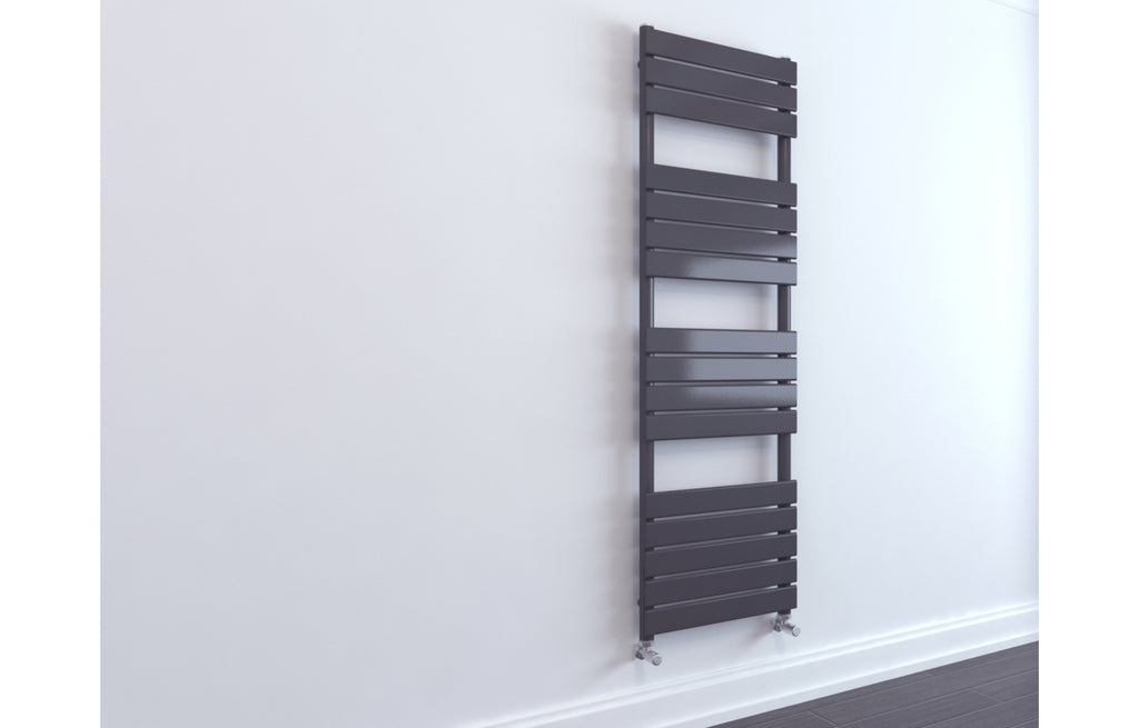 Tall narrow dark gray radiator against a white wall